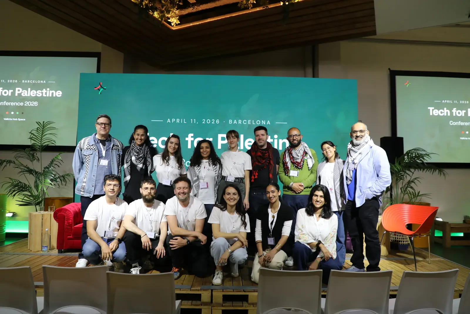 Tech for Palestine volunteers in T4P shirts and keffiyehs on stage at the 2026 Barcelona conference